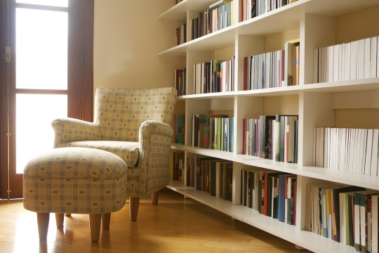 fotel obok półek z książkami